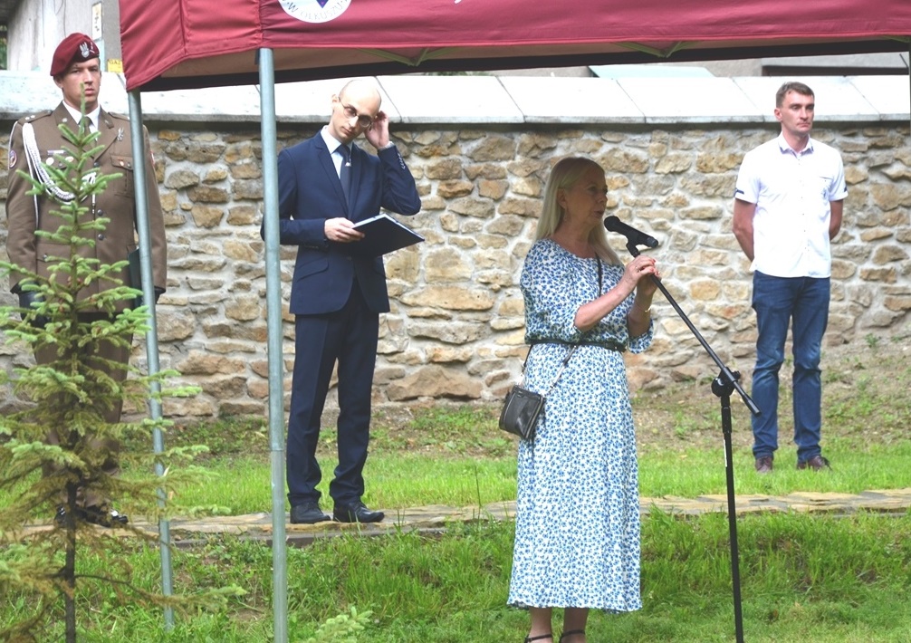 Kobieta w niebieskiej sukience przemawia podczas uroczystości.