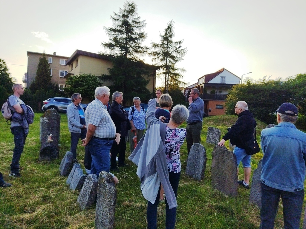 Grupa osób stoi na dawnym cmentarzu żydowskim w Olkuszu.